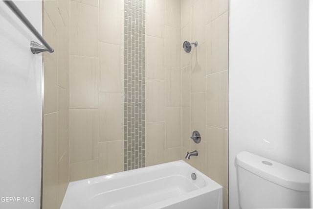 bathroom featuring tiled shower / bath combo and toilet