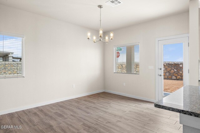 unfurnished dining area with an inviting chandelier and light wood-type flooring