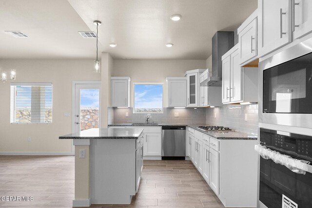 kitchen with hanging light fixtures, stainless steel appliances, a center island, tasteful backsplash, and white cabinets