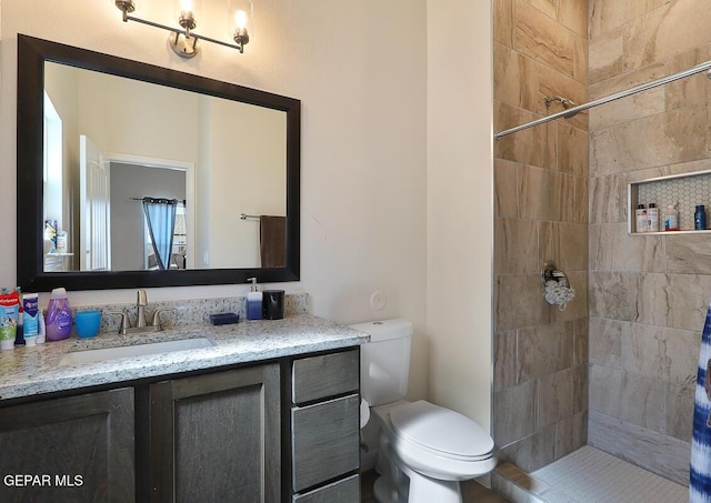 bathroom featuring toilet, vanity, and tiled shower