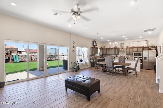 living room featuring a healthy amount of sunlight and ceiling fan with notable chandelier