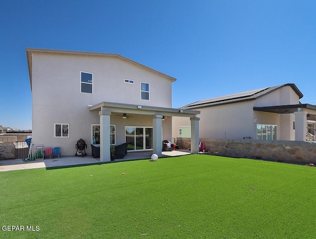 rear view of house with ceiling fan, a patio area, and a lawn