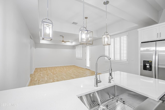 kitchen with sink, white cabinetry, a raised ceiling, pendant lighting, and light hardwood / wood-style floors