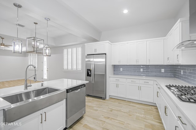 kitchen with white cabinetry, appliances with stainless steel finishes, sink, and wall chimney range hood