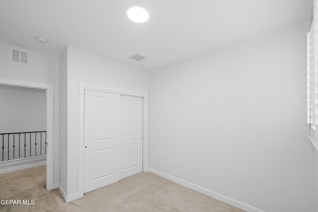 unfurnished bedroom featuring light colored carpet and a closet