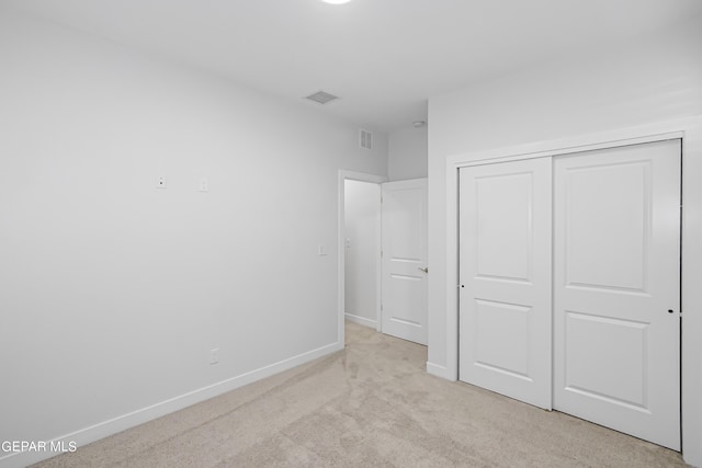 unfurnished bedroom with a closet and light carpet