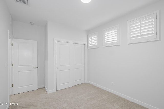 unfurnished bedroom featuring light colored carpet and a closet