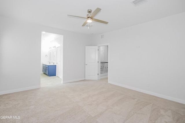 unfurnished bedroom featuring light carpet, connected bathroom, sink, and ceiling fan