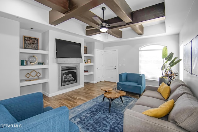 living room with ceiling fan, coffered ceiling, wood-type flooring, built in shelves, and beamed ceiling