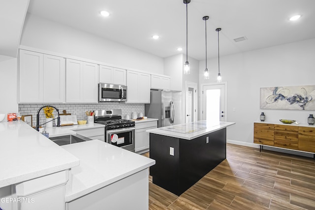 kitchen with decorative light fixtures, white cabinetry, sink, a center island, and stainless steel appliances