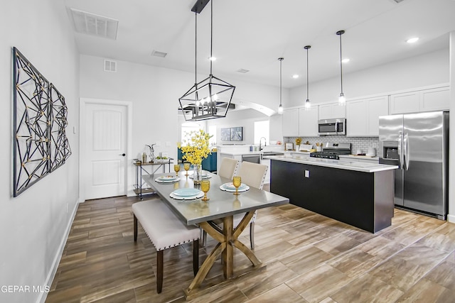 kitchen featuring a kitchen island, pendant lighting, white cabinetry, backsplash, and stainless steel appliances