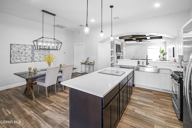 kitchen featuring pendant lighting, sink, coffered ceiling, dark brown cabinetry, and stainless steel appliances