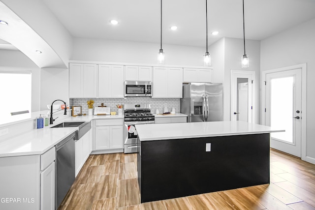 kitchen with sink, stainless steel appliances, a center island, white cabinets, and decorative light fixtures