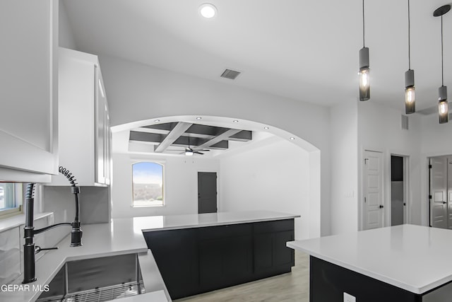 kitchen with coffered ceiling, sink, a center island, hanging light fixtures, and ceiling fan