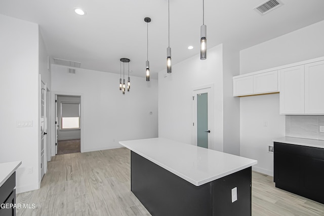 kitchen featuring hanging light fixtures, a kitchen island, white cabinets, and light hardwood / wood-style flooring