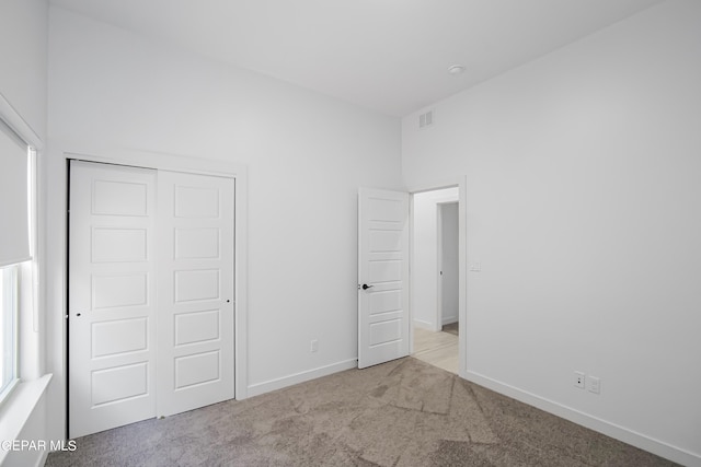 unfurnished bedroom featuring light colored carpet and a closet