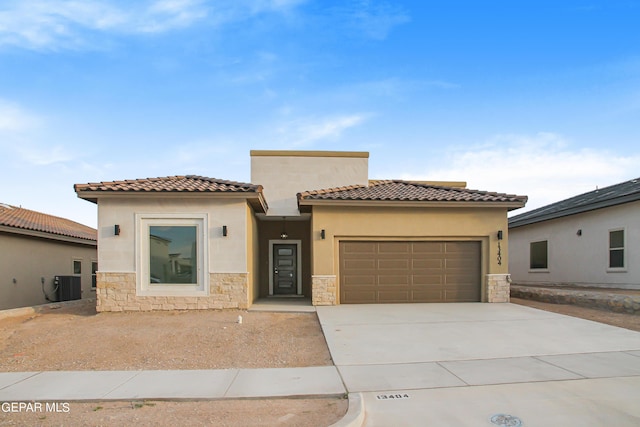 mediterranean / spanish house with a garage and central air condition unit