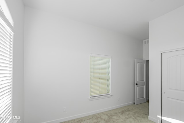 empty room with light colored carpet and a healthy amount of sunlight