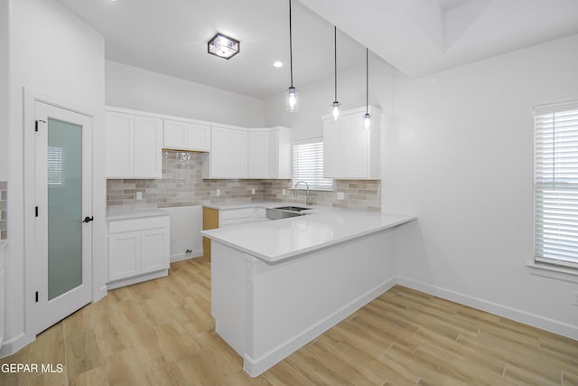 kitchen with white cabinetry, sink, pendant lighting, and light wood-type flooring