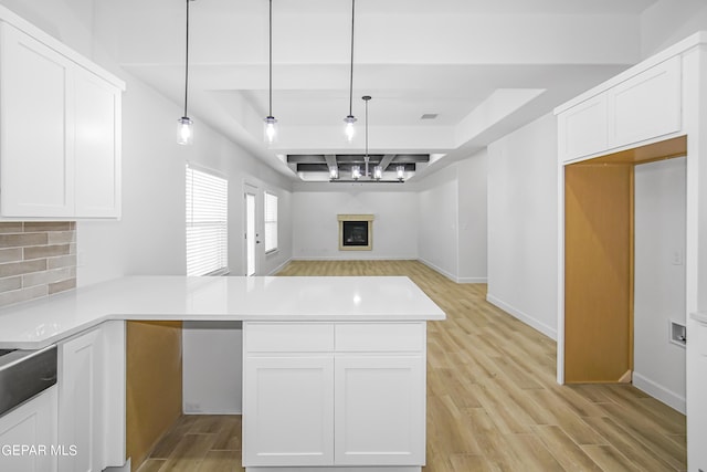 kitchen with decorative light fixtures, kitchen peninsula, and white cabinets