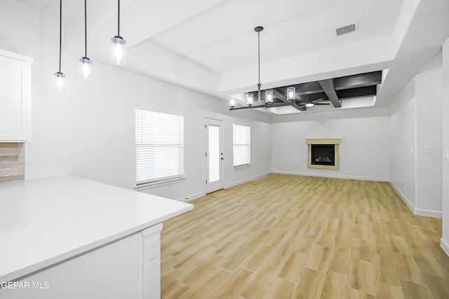 unfurnished living room featuring coffered ceiling, light hardwood / wood-style flooring, a chandelier, and beamed ceiling