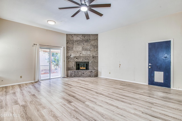 unfurnished living room with light hardwood / wood-style floors, ceiling fan, and a tiled fireplace