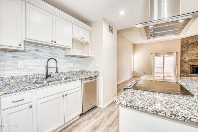 kitchen featuring stainless steel dishwasher, sink, light wood-type flooring, white cabinets, and black electric cooktop