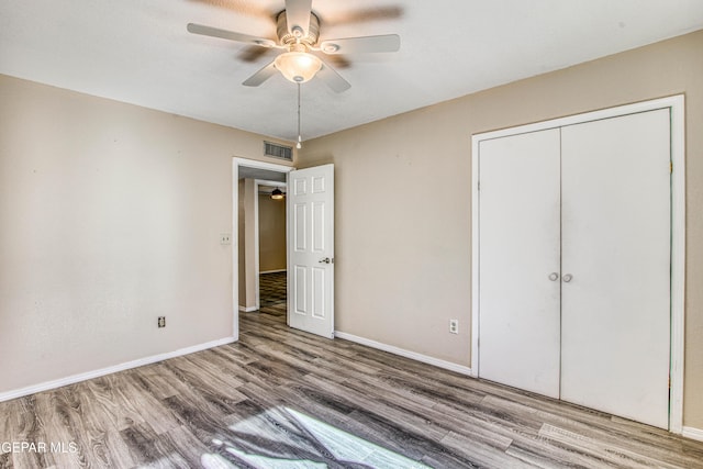 unfurnished bedroom featuring ceiling fan, a closet, and hardwood / wood-style flooring