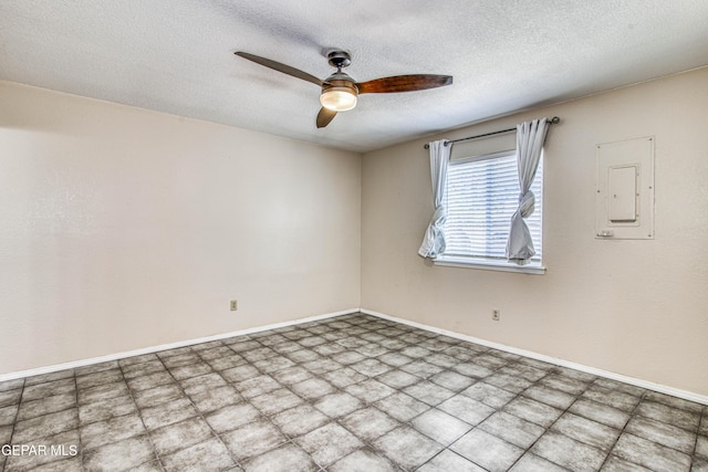 spare room with a textured ceiling, ceiling fan, and electric panel