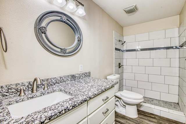 bathroom featuring toilet, vanity, and a tile shower