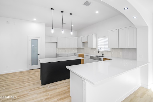 kitchen with sink, decorative light fixtures, a center island, white cabinets, and backsplash