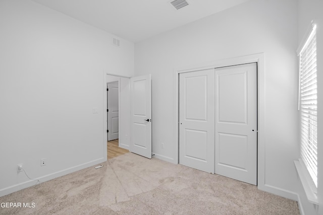 unfurnished bedroom with light colored carpet and a closet