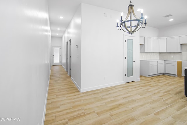 kitchen with white cabinetry, decorative light fixtures, tasteful backsplash, and light wood-type flooring