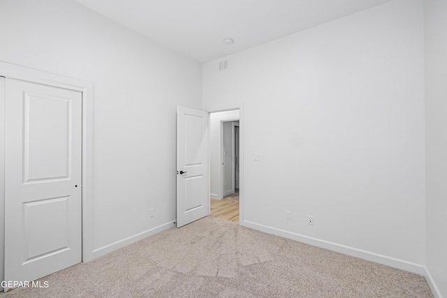 unfurnished bedroom with light colored carpet and a closet