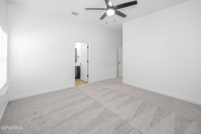 spare room with ceiling fan, plenty of natural light, and light carpet