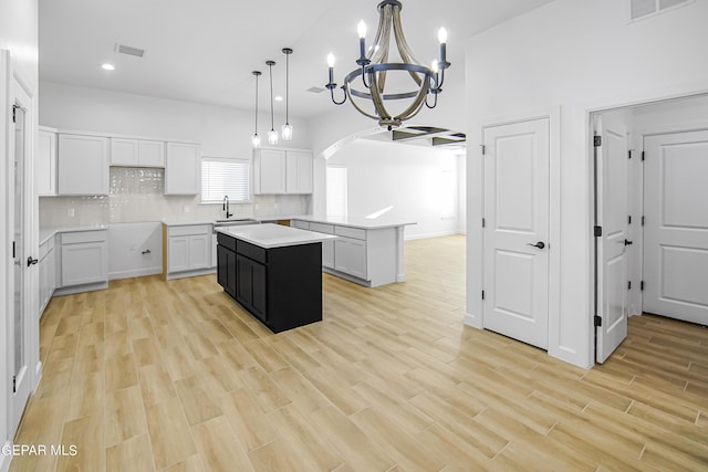 kitchen featuring sink, white cabinetry, a kitchen island, pendant lighting, and decorative backsplash