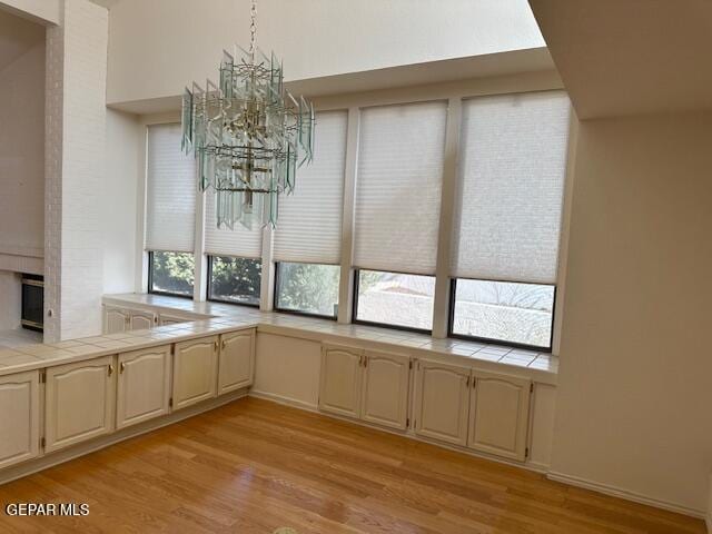 unfurnished dining area with light wood-type flooring and an inviting chandelier