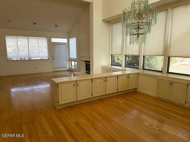 kitchen featuring light wood-type flooring, a wealth of natural light, kitchen peninsula, and an inviting chandelier