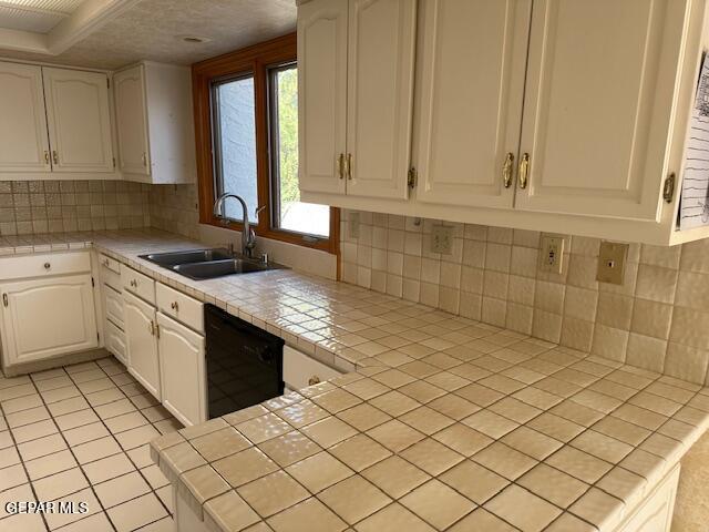 kitchen featuring decorative backsplash, sink, white cabinetry, and tile countertops