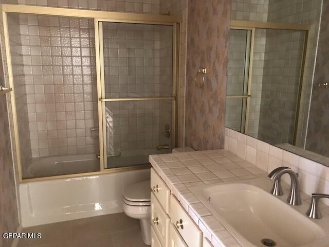 full bathroom with vanity, toilet, bath / shower combo with glass door, and tile patterned flooring