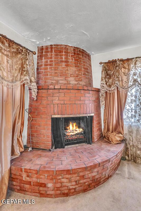 interior details with a brick fireplace, carpet, and a textured ceiling