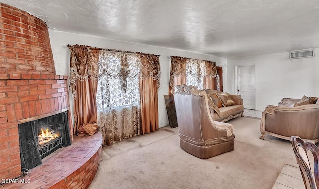 carpeted living room featuring a brick fireplace and a textured ceiling