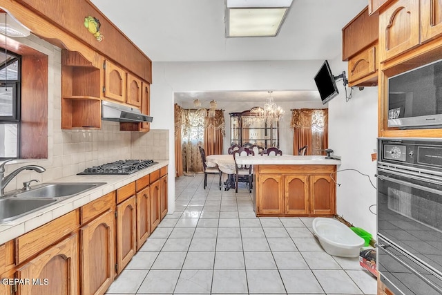 kitchen with gas stovetop, sink, decorative light fixtures, black oven, and light tile patterned flooring