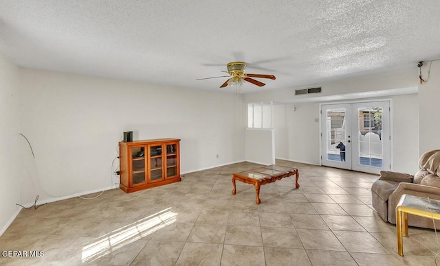 tiled living room featuring ceiling fan, a textured ceiling, and french doors