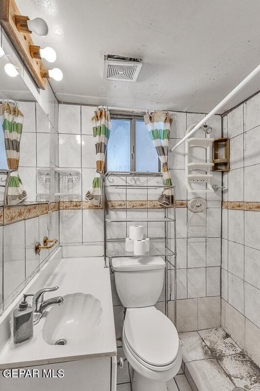 bathroom featuring tile walls, toilet, vanity, and a shower with shower curtain