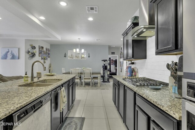 kitchen featuring sink, wall chimney exhaust hood, light stone counters, and appliances with stainless steel finishes