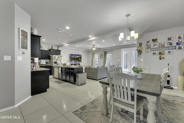 tiled dining area with ceiling fan with notable chandelier and french doors