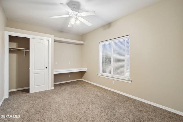 unfurnished bedroom with ceiling fan, a closet, carpet floors, and built in desk