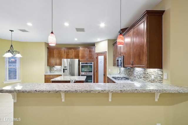 kitchen with stainless steel appliances, a kitchen bar, pendant lighting, and tasteful backsplash