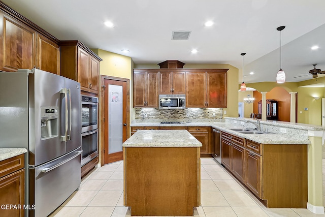 kitchen with appliances with stainless steel finishes, a kitchen island, decorative light fixtures, sink, and kitchen peninsula